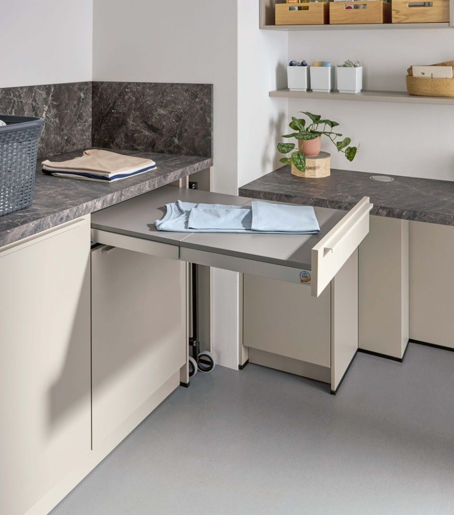 Schublade in einer modernen Küchenzeile mit Wäsche und Pflanzen auf der Ablage.