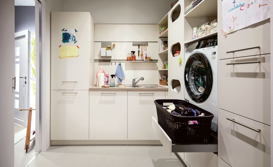 Moderne Waschküche mit Waschmaschine, Schränken und einem Wäschekorb auf einer Arbeitsfläche.