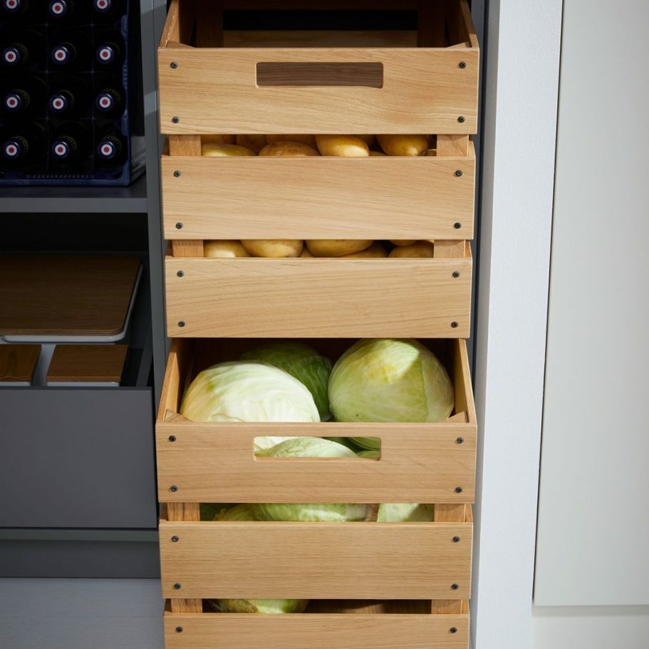 Holzkistenturm mit Äpfeln und Kürbissen in einer modernen Küchenecke.